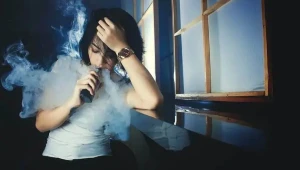 girl vaping while leaning on a window - Can I bring a Juul on a plane as a minor?