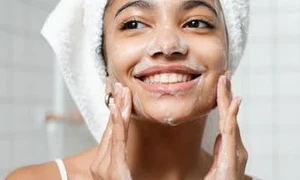 woman washing her face - can i bring face wash on a plane?