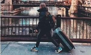 Man walking over a European bridge with a large hard sided suitcase. What size luggage holds 50 lbs?