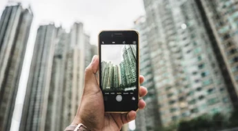 Man holding a phone and taking a picture of a cityscape - Which phones and not allowed on planes?