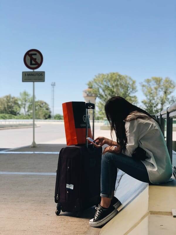 Woman Sitting Down Next to Luggage